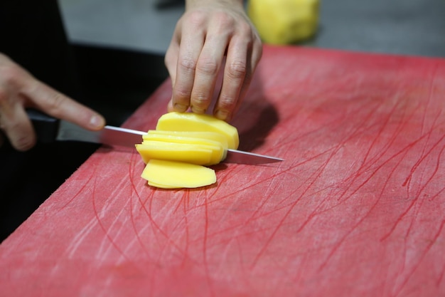 El hombre corta las papas para cocinar.