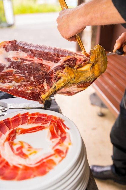 Hombre cortador de jamón ibérico Servicio de una persona cortando un trozo de jamón Chef o cortador con un cuchillo cortando lonchas comida tradicional de españa