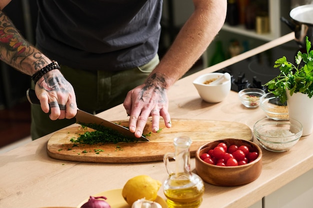 Foto hombre cortando cilantro fresco en la mesa