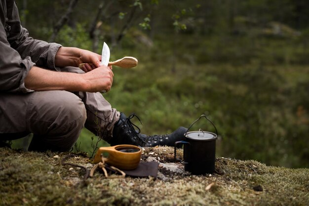 Foto hombre cortando una cuchara en el bosque