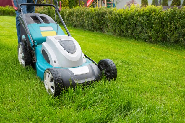 Un hombre cortando hierba con una cortadora de césped en el jardín en un día soleado