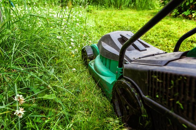 Hombre cortando hierba verde con cortadora de césped en el patio trasero Fondo de estilo de vida rural de jardinería Hermosa vista sobre césped de hierba verde fresca en el paisaje del jardín de la luz del sol en primavera o verano