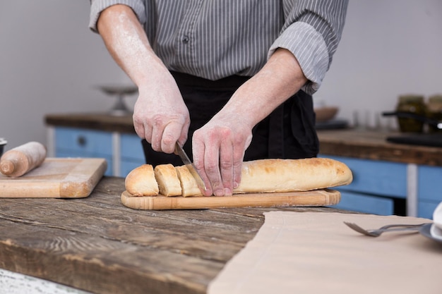 Hombre cortando pan en la cocina