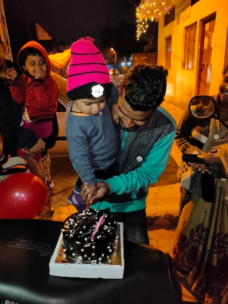 Foto hombre cortando pastel mientras lleva a un niño por la noche