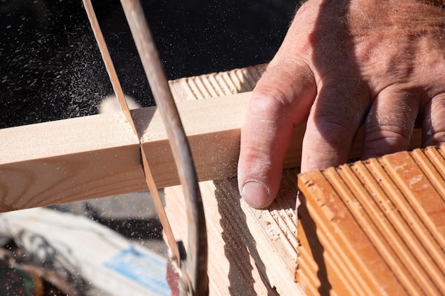 Un hombre cortando un trozo de madera con una sierra para metal