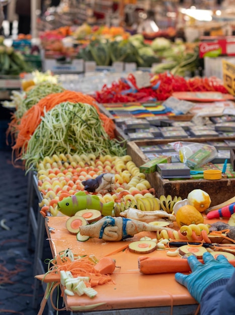 Foto hombre cortando verduras con diferentes formas en el mercadillo al aire libre