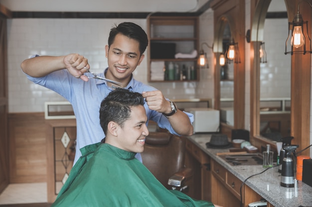 Hombre cortarse el pelo por peluquero en peluquería