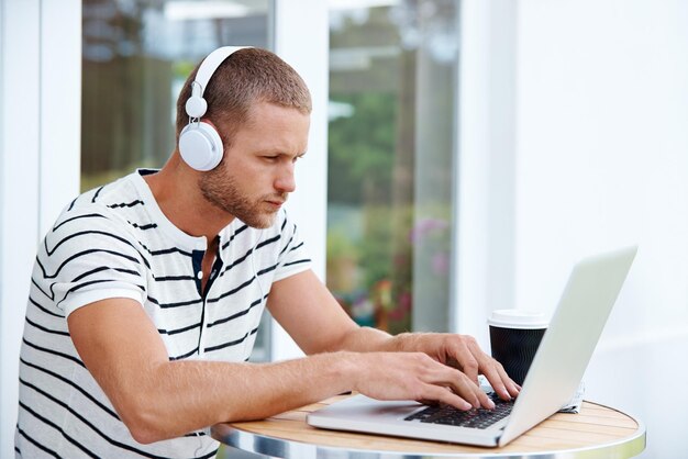 Hombre creativo y escribiendo al aire libre en una computadora portátil en el patio trasero para el trabajo remoto redactando presentaciones para los medios de comunicación y comunicados de prensa Hombre publicista auriculares y en línea para administrar cuentas sociales o planificar campañas
