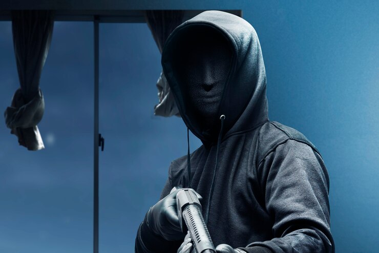 Foto hombre criminal en una máscara oculta sosteniendo la escopeta mientras roba la casa en la noche