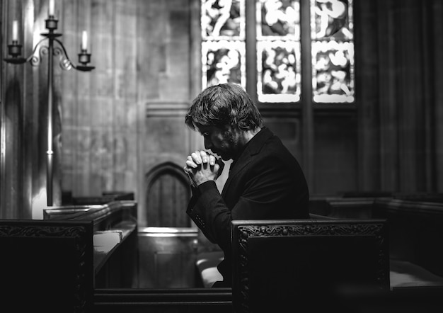 Hombre cristiano solitario rezando en la iglesia.