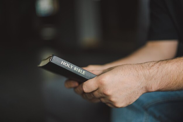 El hombre cristiano sostiene la Santa Biblia en las manos Leyendo la Santa Biblia en un hogar Concepto de fe espiritualidad y religión Esperanza de paz