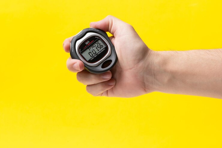 Foto hombre con un cronómetro en la mano en primer plano de fondo amarillo concepto de gestión del tiempo