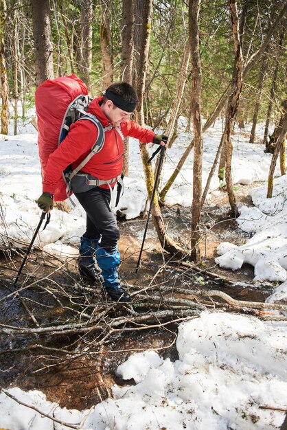 Un hombre cruzando un arroyo en un bosque