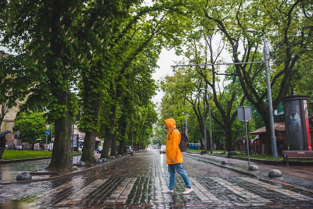 Hombre cruzando la calle con impermeable amarillo clima nublado