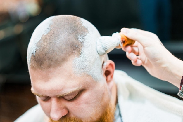 Un hombre se cubre la cabeza con gel de afeitar en la barbería