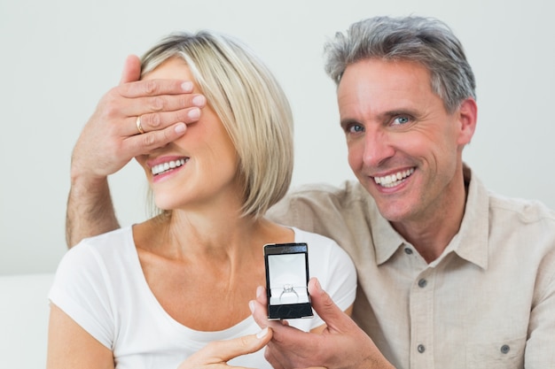 Hombre cubriendo los ojos de mujer para ofrecerle un anillo de compromiso