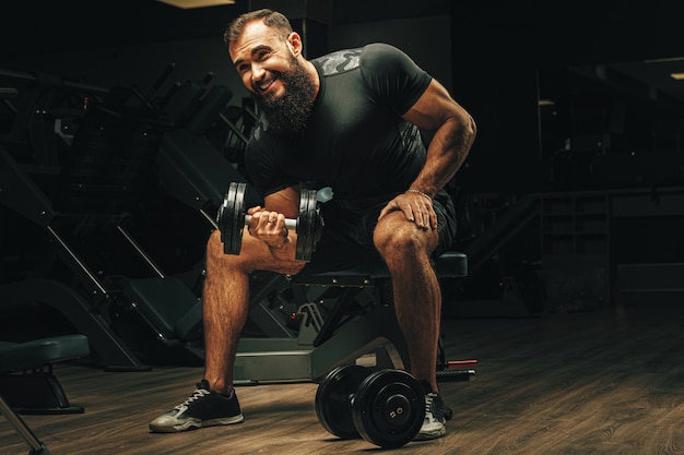 Hombre con cuerpo deportivo levantando pesas en el gimnasio