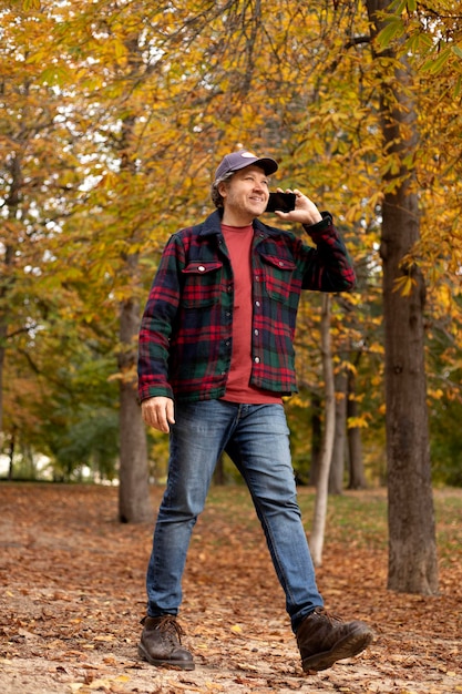 Hombre de cuerpo entero en el bosque hablando por teléfono | Foto Premium