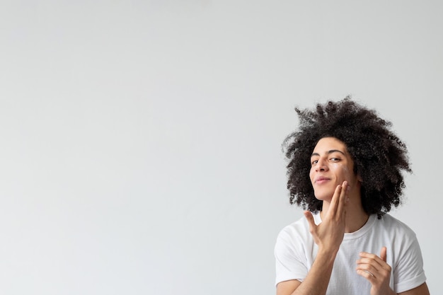 Hombre cuidado de la piel tratamiento facial aseo masculino satisfecho chico guapo con largo cabello castaño rizado applyi