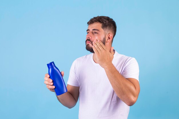 Hombre cuidadoso aplicando crema corporal y facial para hidratar la piel