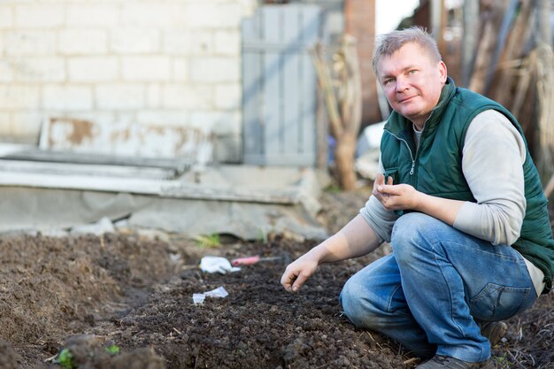 El hombre cultiva las semillas de rábano, en el jardín.