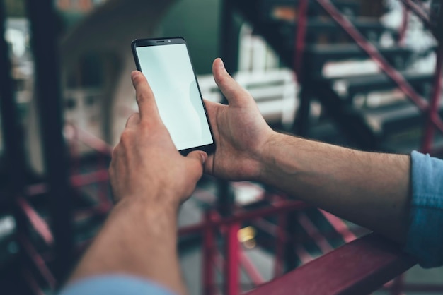 Hombre de cultivo usando un teléfono inteligente cerca de la barandilla