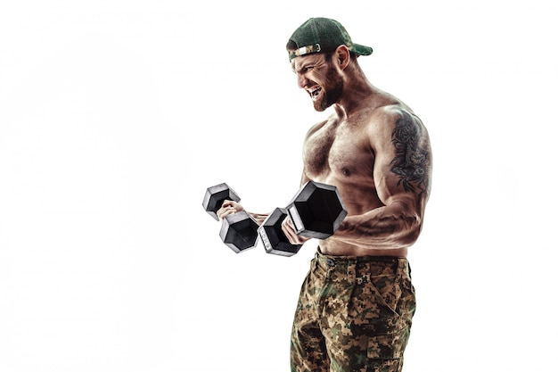 Hombre culturista musculoso atleta en pantalones de camuflaje con un entrenamiento de torso desnudo con mancuernas.