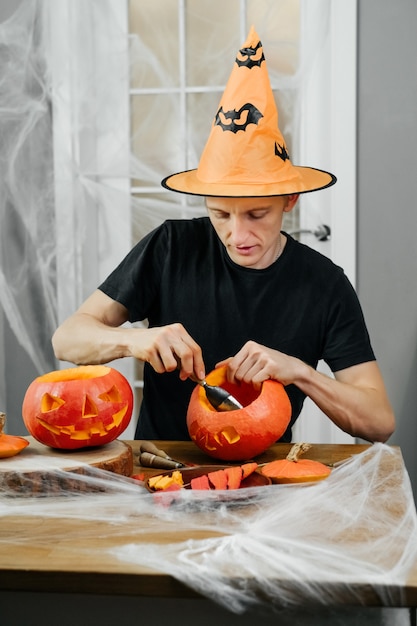 Hombre curva jac o lanten calabaza Helloween en casa. Preparándose para las vacaciones