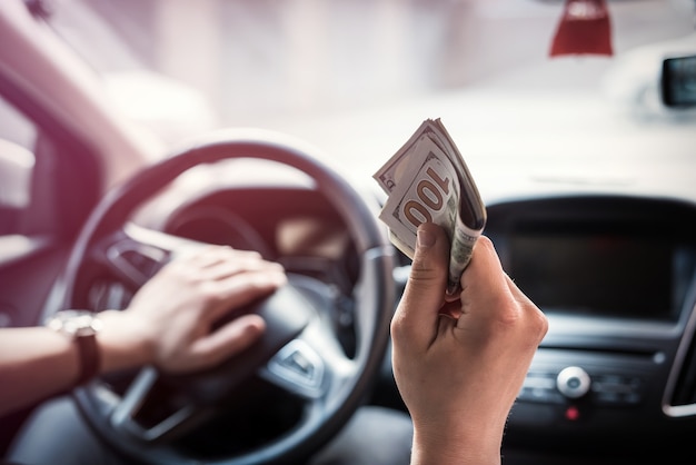 El hombre da dólares mientras está sentado en el coche. concepto de compras, dinero