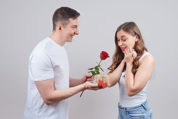 El hombre le da a una mujer una rosa roja como regalo.