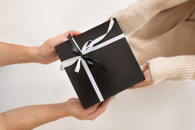 Un hombre le da un regalo envuelto festivo a una mujer Primer plano en una caja de regalo en la vista superior de las manos