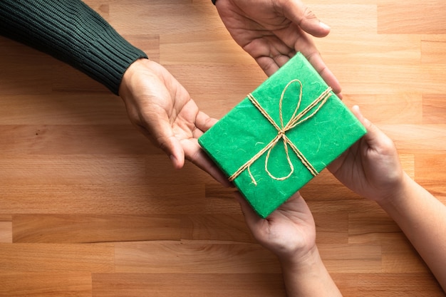 Hombre da un regalo a mujer en mesa de madera