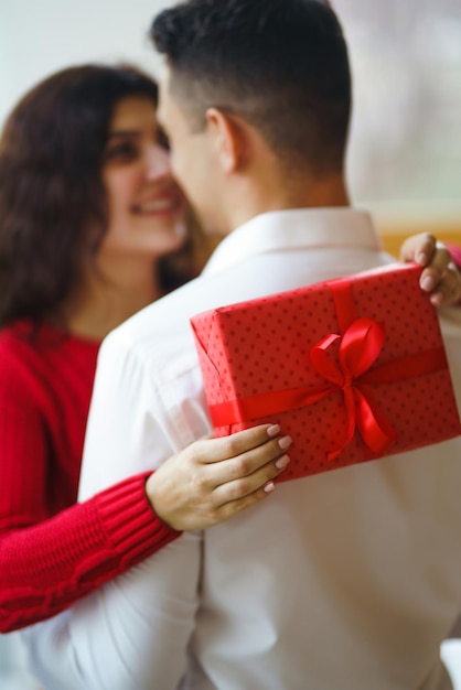 El hombre le da a su mujer una caja de regalo con cinta roja Una pareja amorosa celebrando el Día de San Valentín