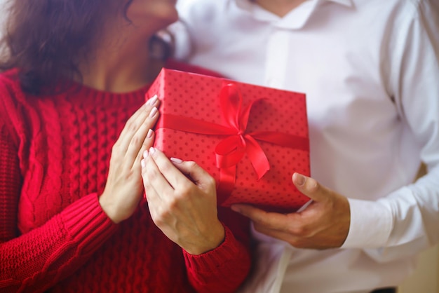 El hombre le da a su mujer una caja de regalo con cinta roja Una pareja amorosa celebrando el Día de San Valentín