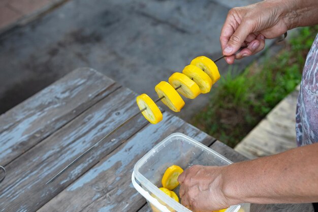 Foto un hombre da la vuelta a las pinzas de comida y asada trozos a la parrilla de calabacín calabazas pequeñas cebollas rojas zanahorias en una barbacoa parrilla en carbón en brazier en el jardín en verano verdura útil para un picnic