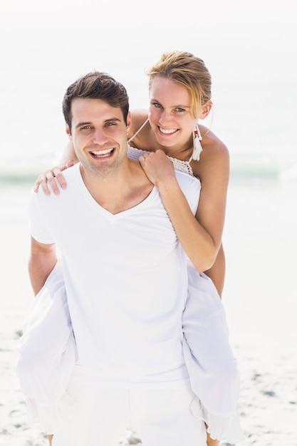 Hombre dando un piggy back a mujer en la playa