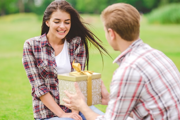 Foto el hombre dando un regalo a una mujer al aire libre.