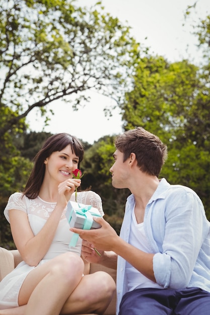 Hombre dando un regalo sorpresa y una rosa para mujer al aire libre