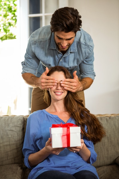 Foto hombre dando un regalo sorpresa a su mujer