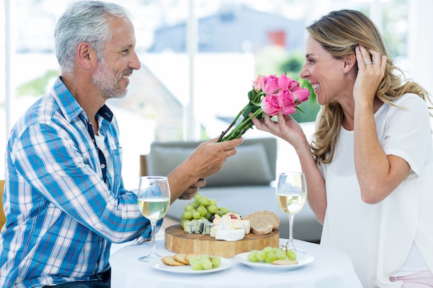 Hombre dando rosas rosas a esposa en restaurante