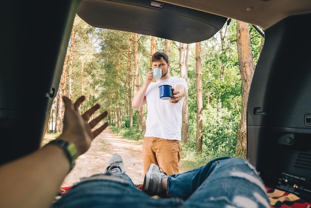 Foto hombre dando taza de metal con espacio de copia de concepto de senderismo de coche de té