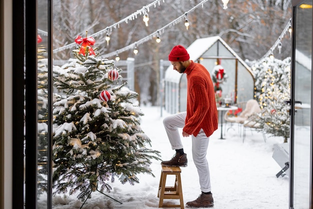 El hombre decora el árbol de navidad en el patio trasero