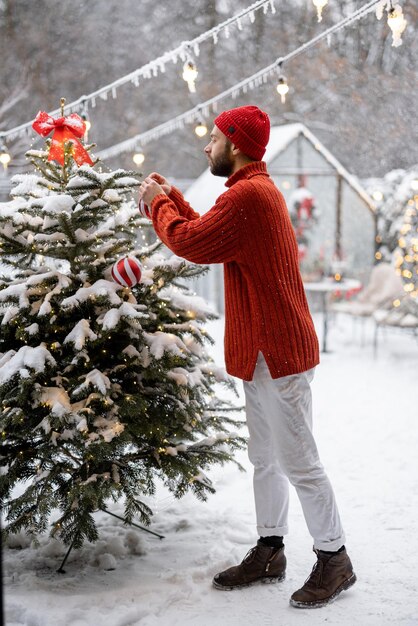 El hombre decora el árbol de navidad en el patio trasero