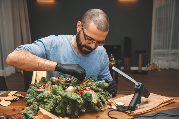 Hombre decorando una corona de Navidad Decoración navideña de año nuevo Decoración de corona de árbol de Navidad DIY