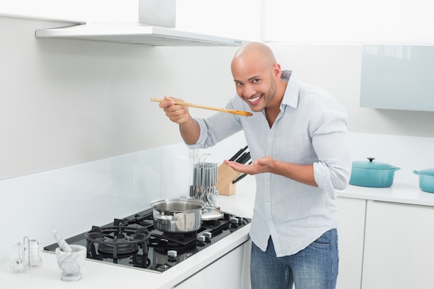 Hombre degustando comida mientras se prepara en la cocina