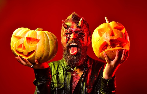 Foto hombre demonio con calabazas sobre fondo rojo concepto de halloween personaje cómico drácula retrato o