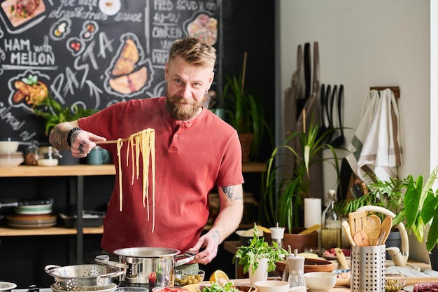 Hombre demostrando pasta cocida en la cocina