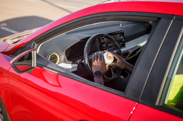 Hombre dentro de un coche rojo con luz de emergencia en el volante