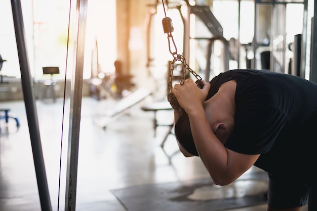 Hombre de deporte asiático que usa equipo de gimnasio de fitness ejercicio en el gimnasio Culturismo asiático para entrenamiento muscular Concepto de gimnasio de salud deportiva