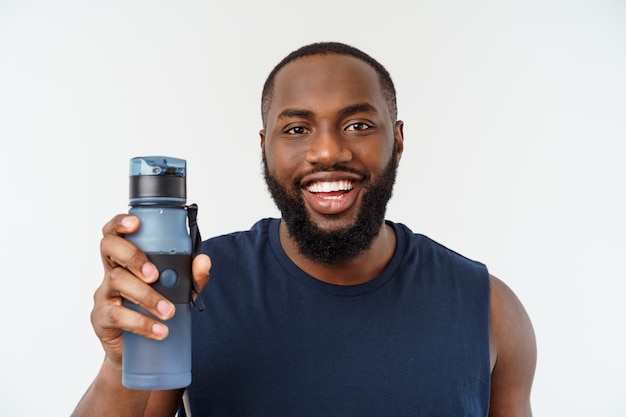 Hombre de deporte atleta masculino afroamericano con correr deportes con teléfono móvil y beber agua de botella.